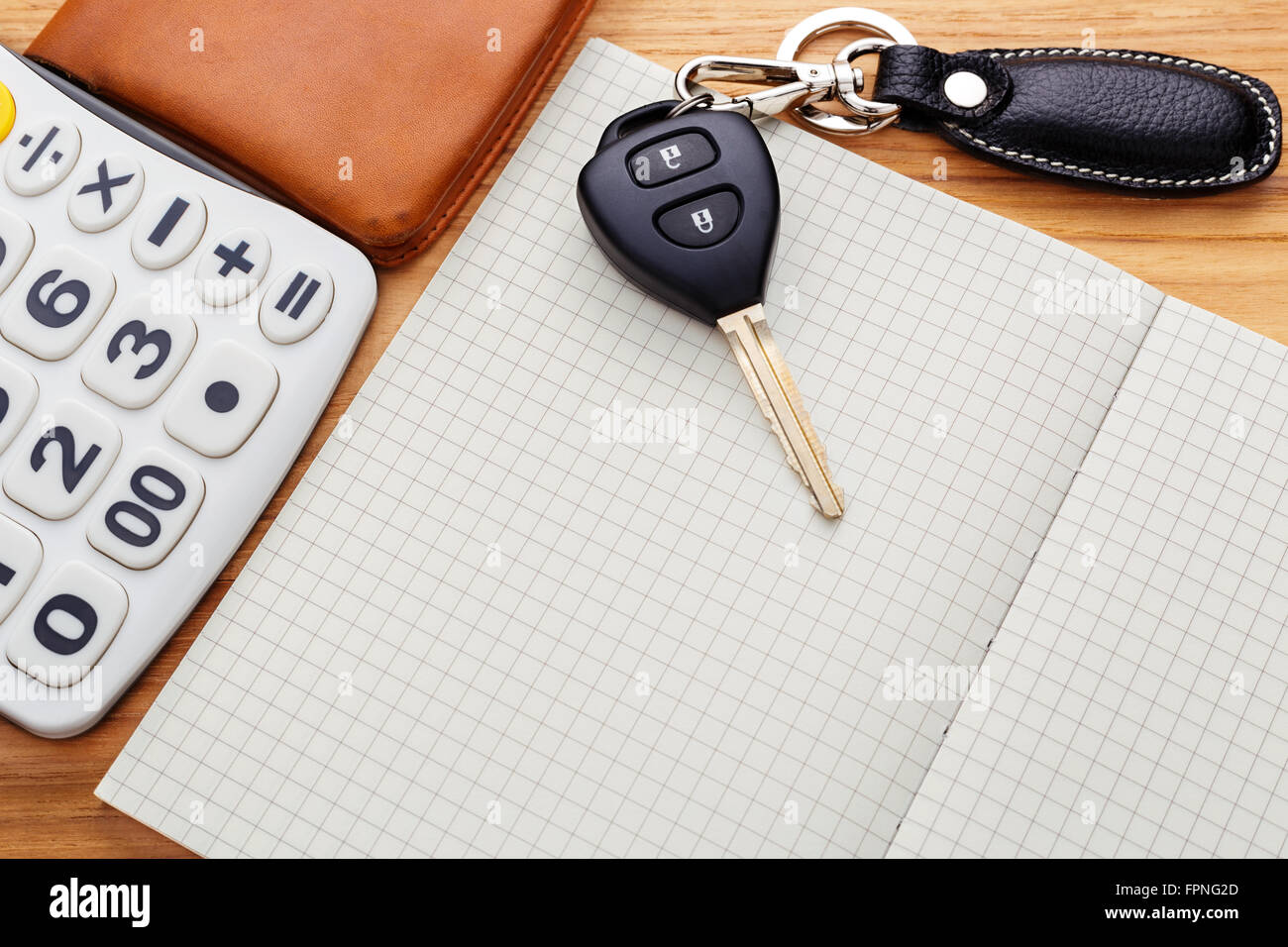 Chiave auto sul notebook vuota con la calcolatrice e pocket money su tavola di legno Foto Stock