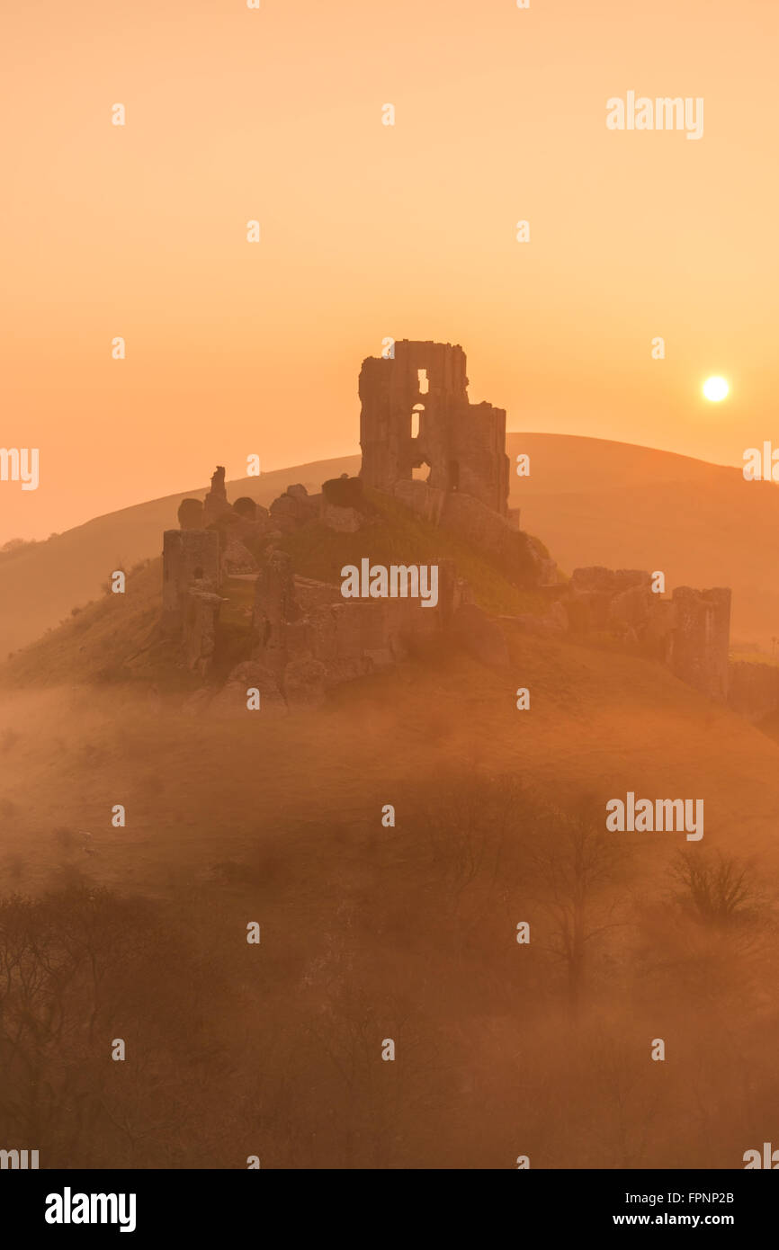 Il sole che tramonta dietro Corfe Castle nel Dorset Foto Stock