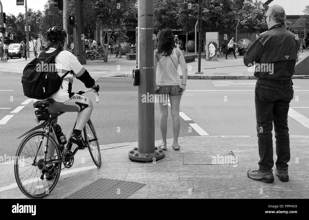 Pedoni e ciclisti di attendere presso il semaforo della strada che attraversa in città di Brisbane Foto Stock