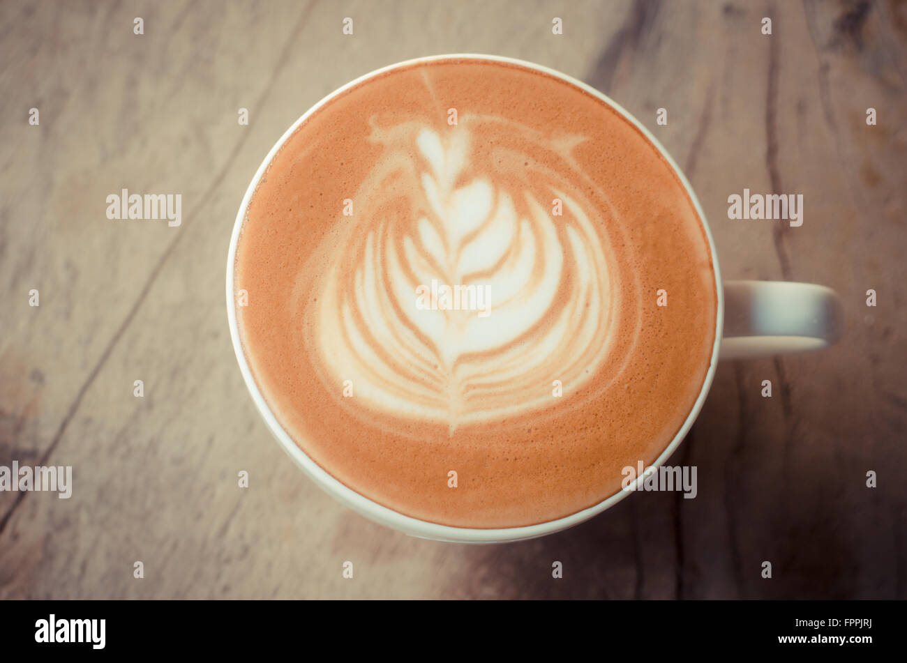 Una tazza di latte art su sfondo di legno, caffè vintage Foto Stock