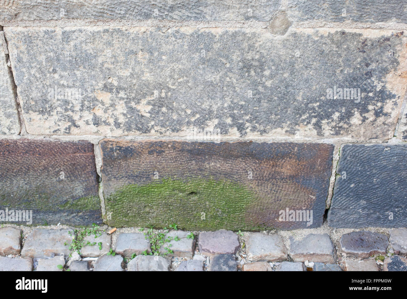 Il vecchio muro di pietra e strada di ciottoli con moss crescente Foto Stock