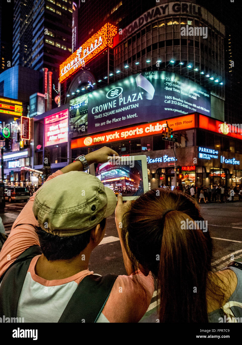 Coppia che scatta una foto su un ipad di Times Square di notte, New York City, USA. Foto Stock