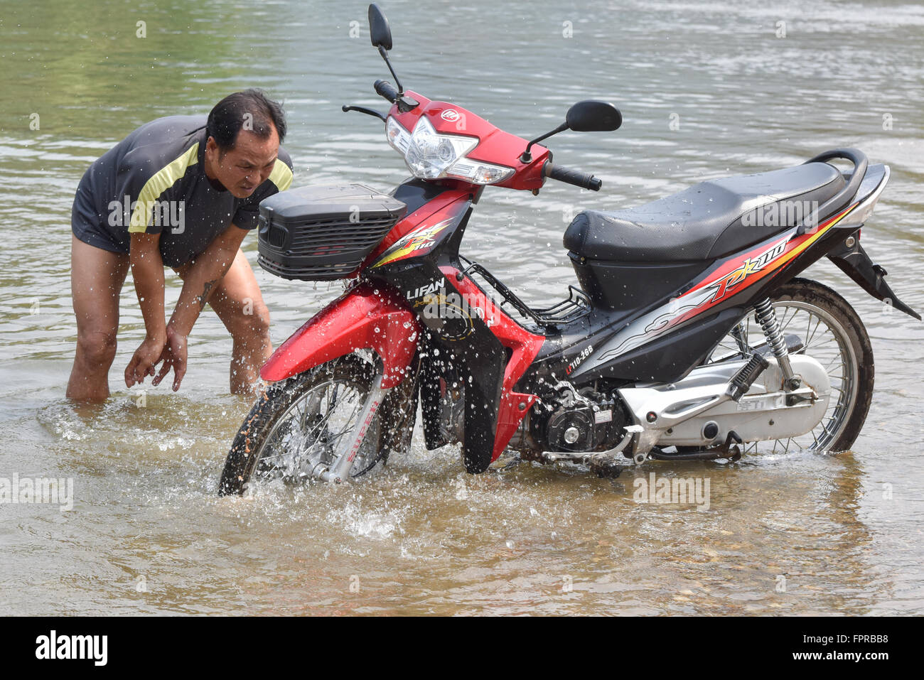 Lavaggio uomo il suo moto nel fiume Mekong Laos Foto Stock