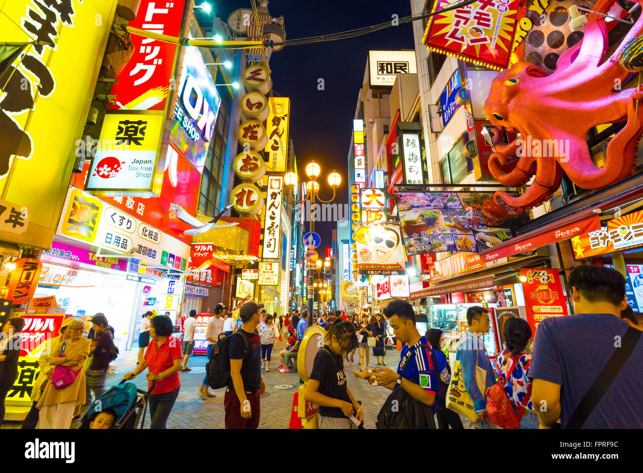 I turisti a piedi attorno a pedonale strada a piedi a arcade Dotonbori sotto l'iconica oversized octopus e luce da notte i segni Foto Stock