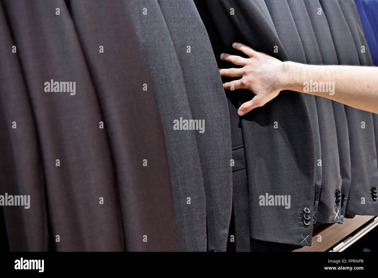 Dettaglio shot con raccolta a mano out man suit jacket in una tuta shop Foto Stock