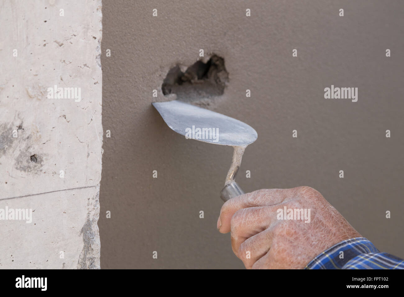 Stretta di mano con cazzuola per finire di calcestruzzo bagnato muro al sito in costruzione Foto Stock