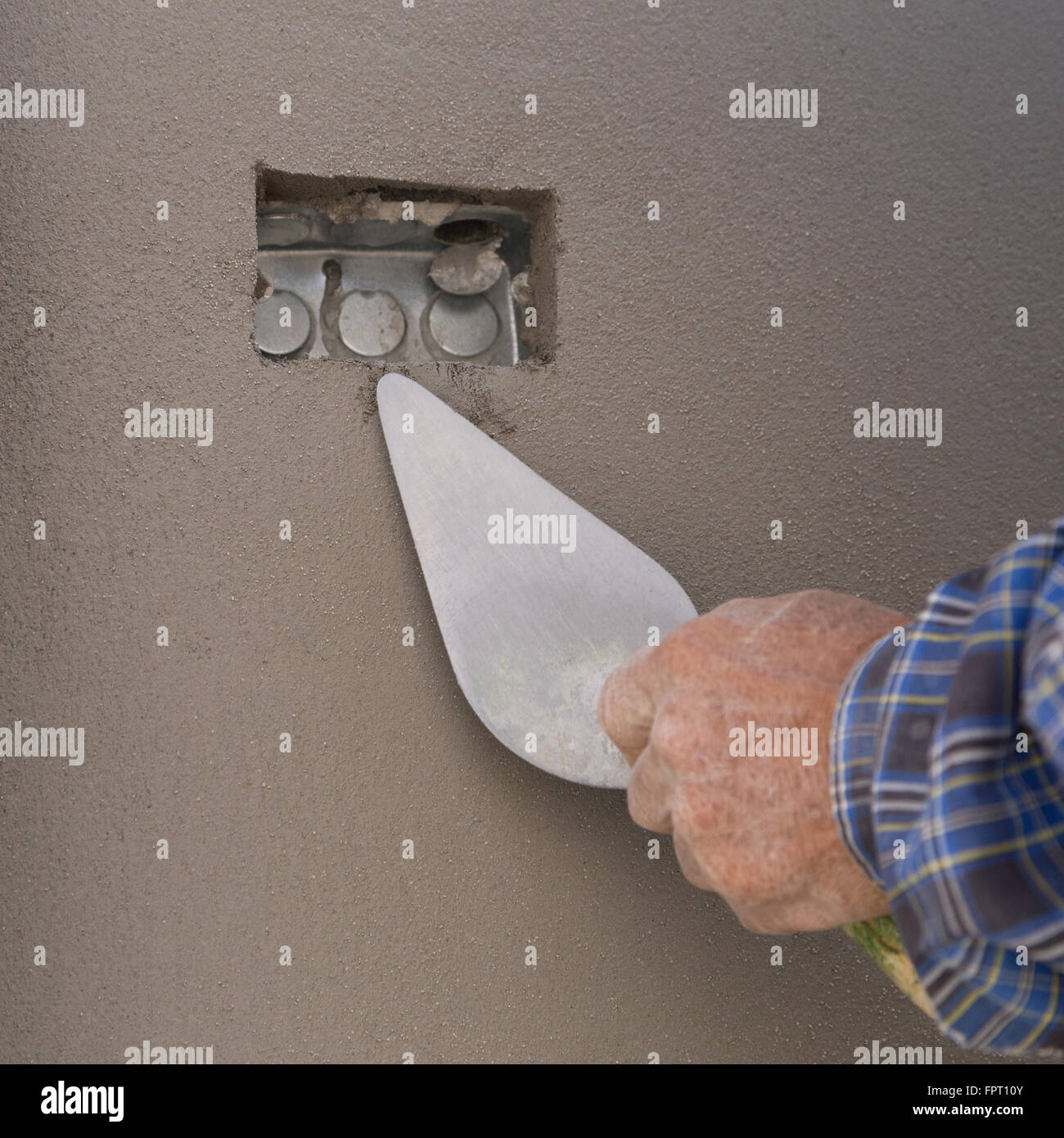 Stretta di mano con cazzuola per finire di calcestruzzo bagnato muro al sito in costruzione Foto Stock