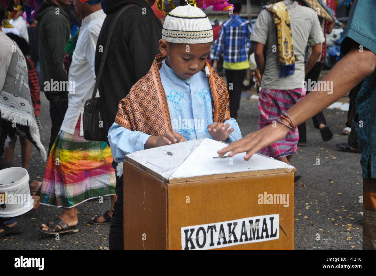 Un capretto inserito un po' di soldi in una carità scatola dopo Eid Al-Fitr preghiera di Makassar, Indonesia il 17 luglio 2015. Foto Stock