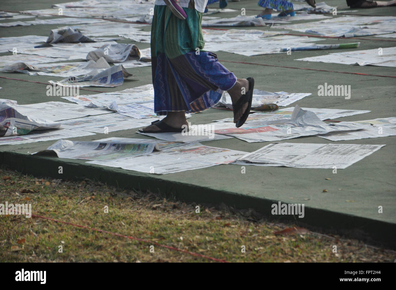 Makassar, Indonesia. La gente a piedi sui fogli di giornale dopo eseguire l'Eid Al Fitr preghiera. Foto Stock