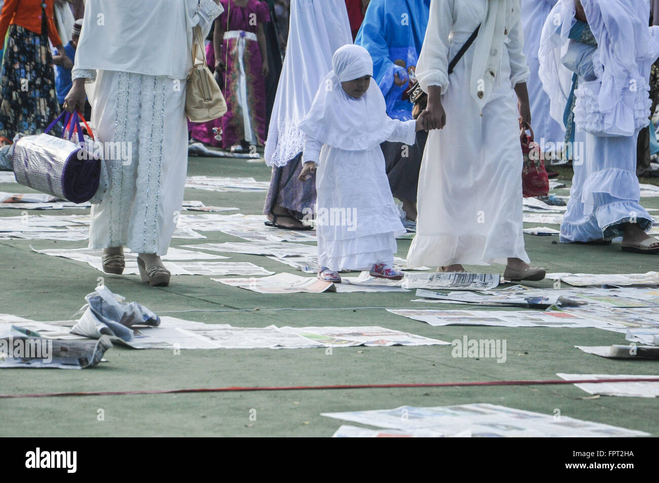 Makassar, Indonesia. La gente a piedi sui fogli di giornale dopo eseguire l'Eid Al Fitr preghiera. Foto Stock