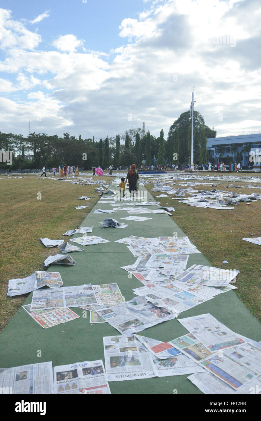 Una madre e suo figlio camminare sui fogli di giornale che utilizzate durante Eid-Al Fitr in Makassar, Indonesia o Luglio 17, 2015 Foto Stock