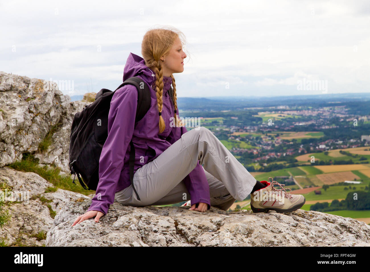 Giovane donna seduta su un picco di montagna Foto Stock