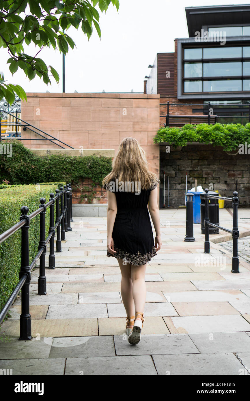 Vista posteriore di una giovane donna che cammina nella città Foto Stock