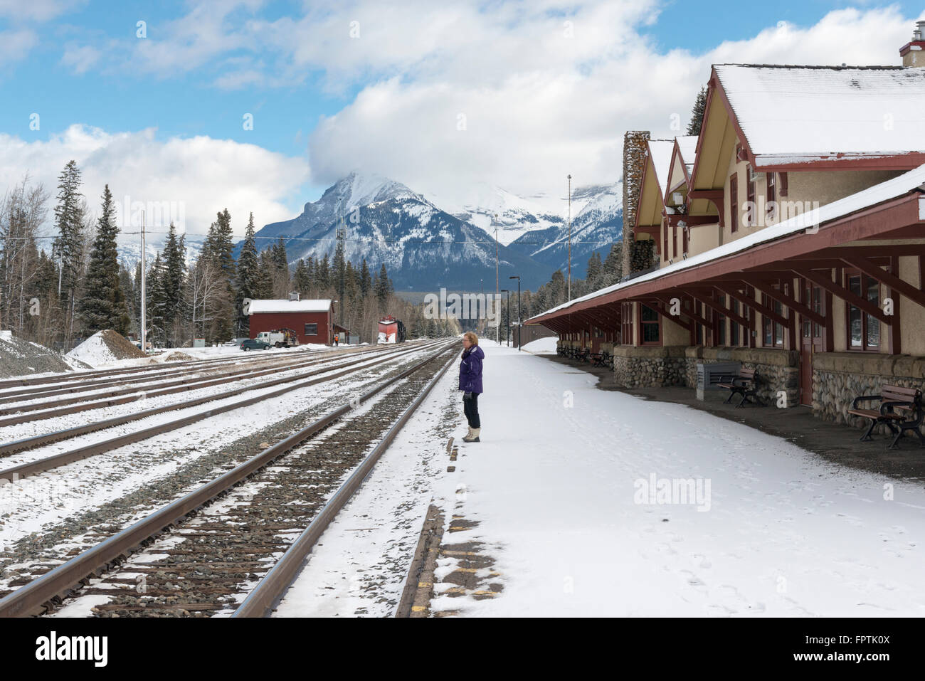 Una donna in piedi a Banff Stazione ferroviaria sulla piattaforma di neve in inverno Foto Stock