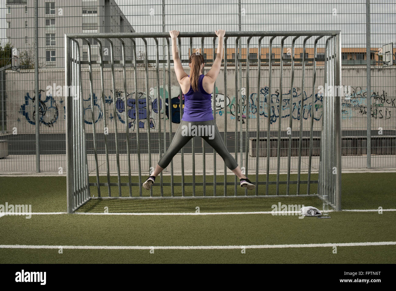 Vista posteriore di una giovane donna facendo chin-ups sul terreno di calcio, Baviera, Germania Foto Stock