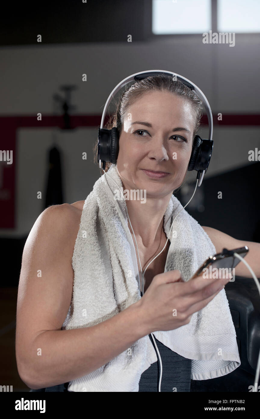 Giovane donna ascoltando musica in palestra durante la pausa, Baviera, Germania Foto Stock