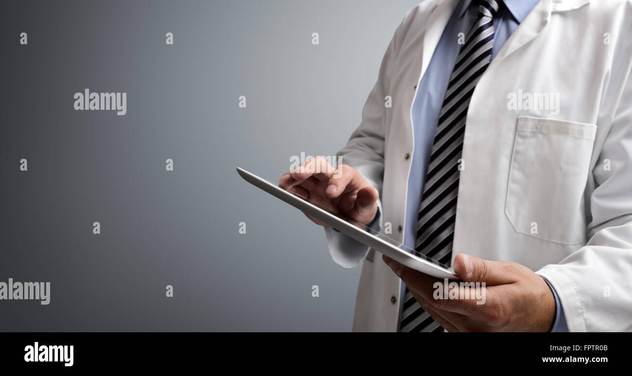 Medico usando tavoletta digitale su sfondo grigio Foto Stock