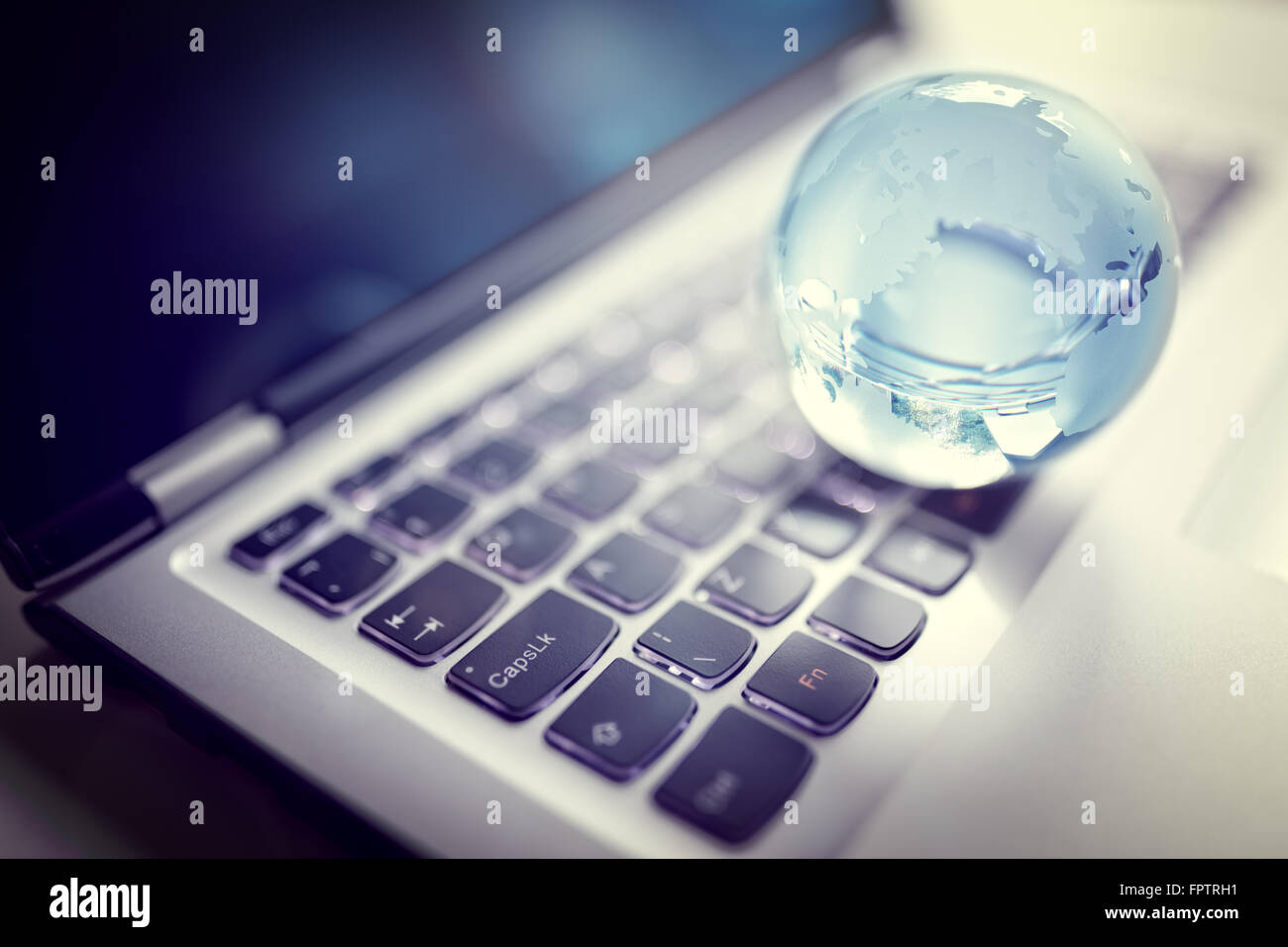 Vetro globo di cristallo sulla tastiera del laptop per il concetto di comunicazione globale e di business Foto Stock