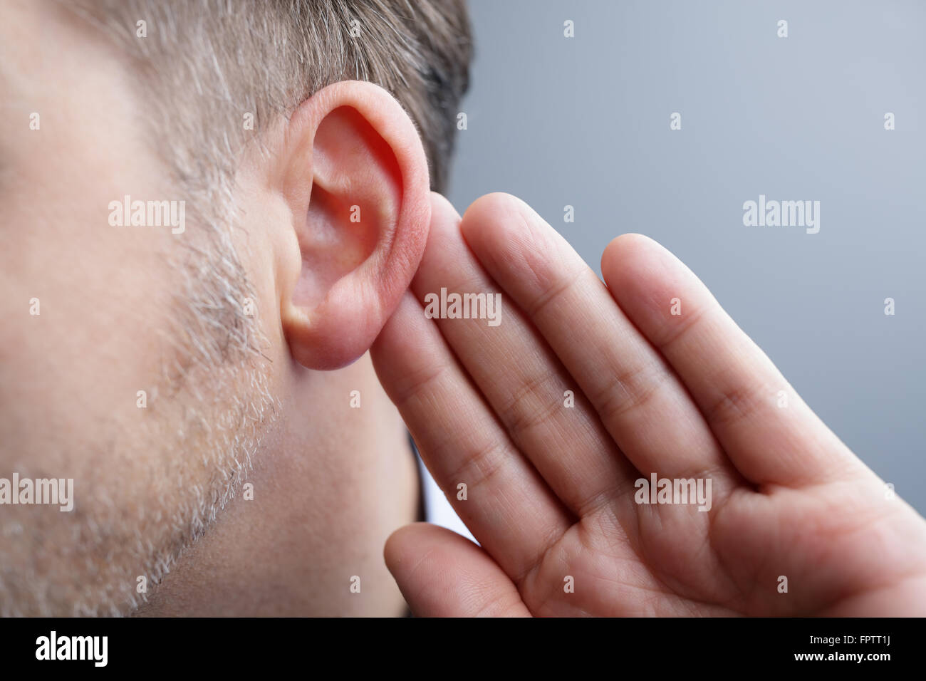 Uomo con mano sul orecchio per ascoltare suono tranquillo o prestando attenzione Foto Stock