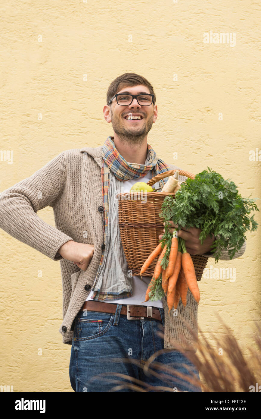 Ritratto di una metà uomo adulto azienda cesto pieno di verdure e sorridente, Baviera, Germania Foto Stock