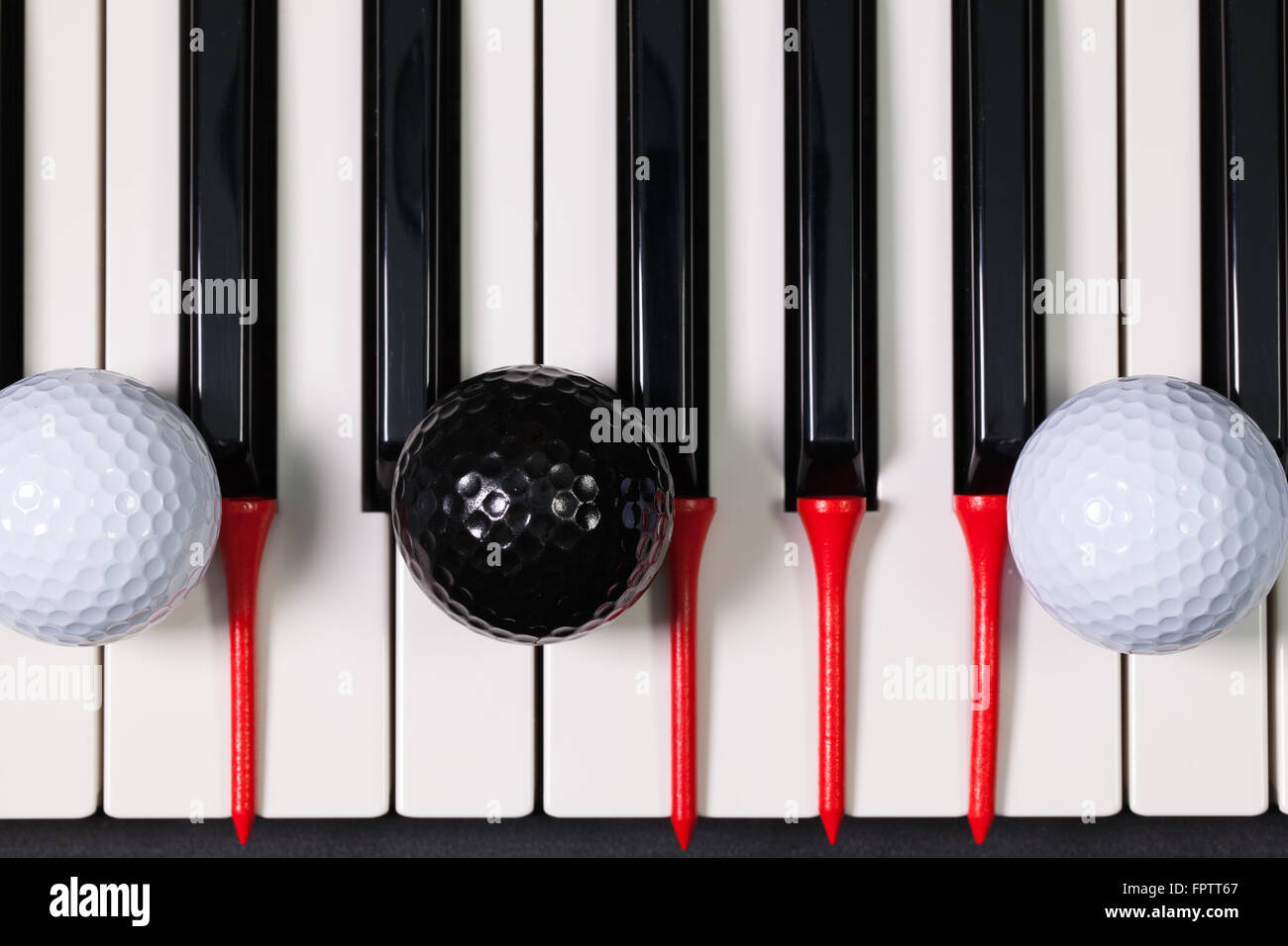 Virtuosi di gioco - Una tastiera di pianoforte e differenti palline da golf e tee di legno Foto Stock