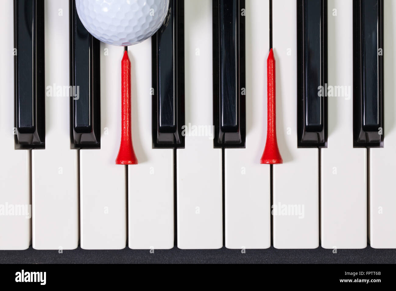 Virtuosi di gioco - Una tastiera di pianoforte e differenti palline da golf e tee di legno Foto Stock