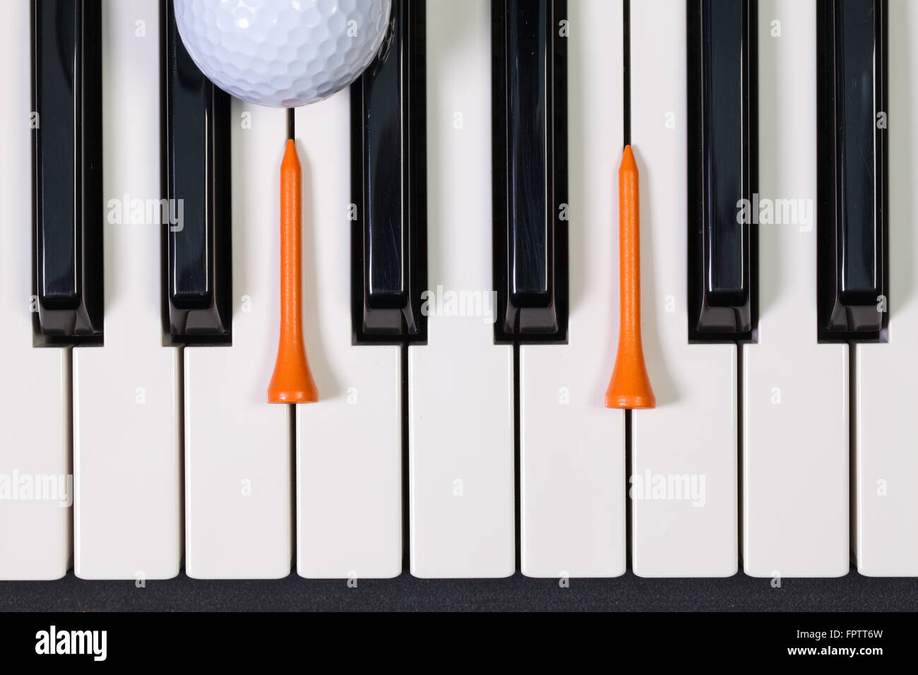 Virtuosi di gioco - Una tastiera di pianoforte e differenti palline da golf e tee di legno Foto Stock
