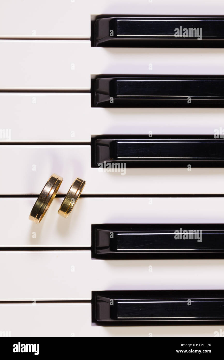 Dettaglio della tastiera di pianoforte e gli anelli di nozze Foto Stock
