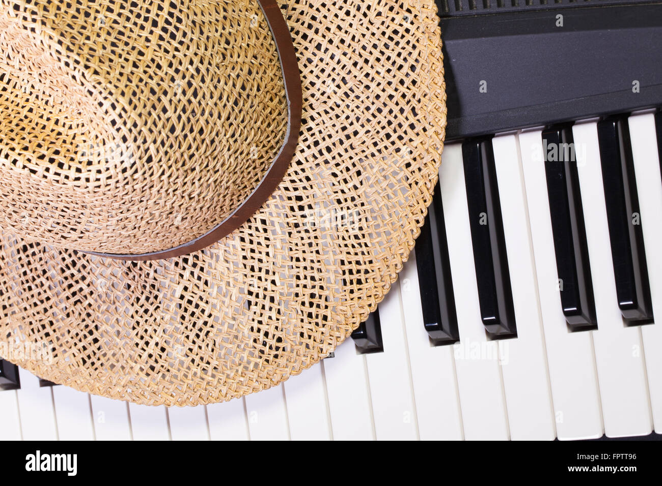 Dettaglio della tastiera di pianoforte e cappello di paglia Foto Stock
