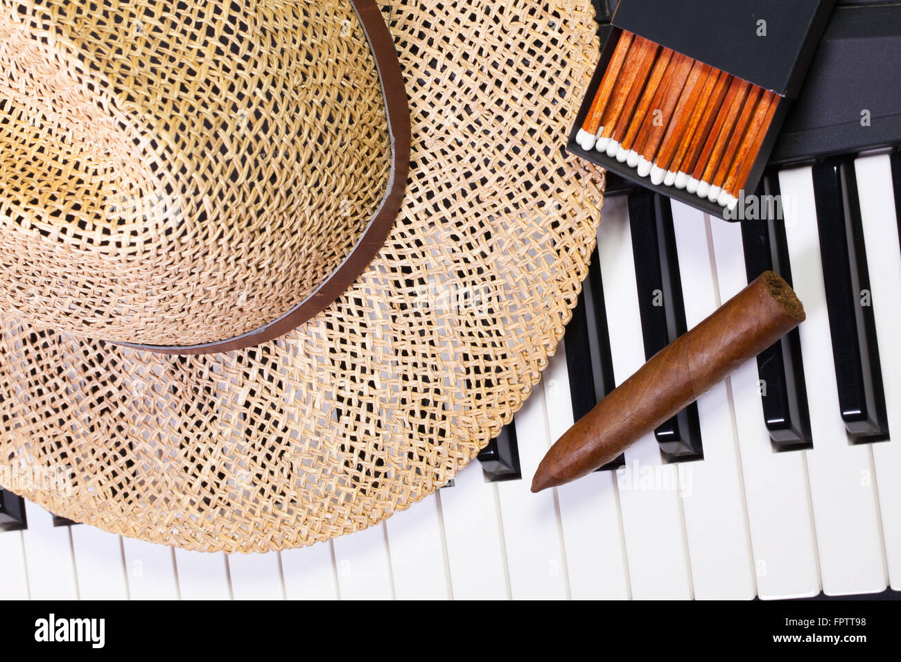 Dettaglio della tastiera di pianoforte,cappello di paglia e sigari di lusso Foto Stock