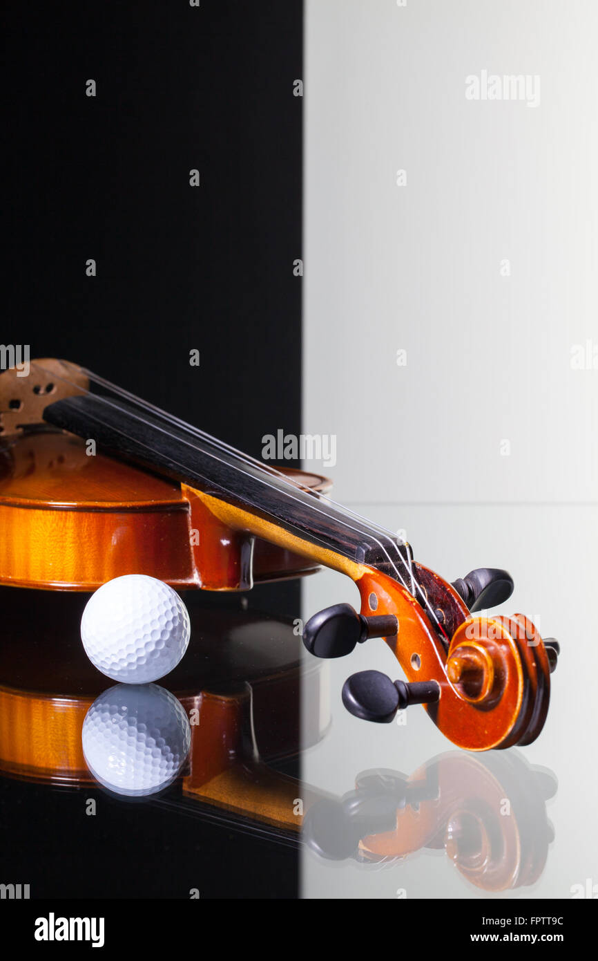 Vecchio violino e pallina da golf isolato in bianco e nero e sfondo scrivania in vetro Foto Stock