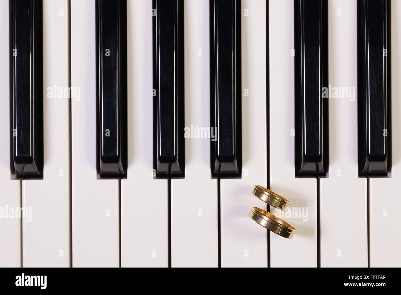 Dettaglio della tastiera di pianoforte e gli anelli di nozze Foto Stock