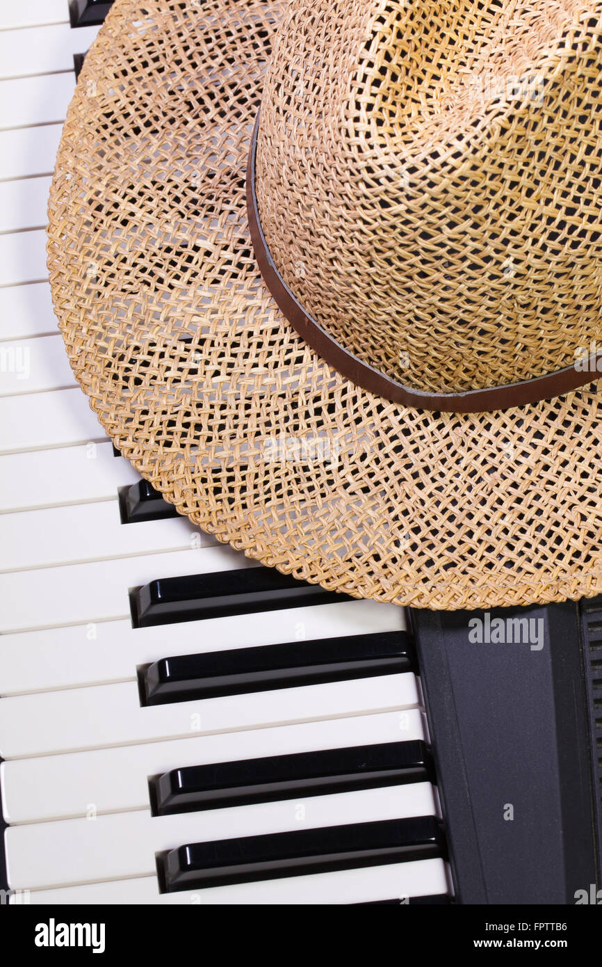 Dettaglio della tastiera di pianoforte e cappello di paglia Foto Stock