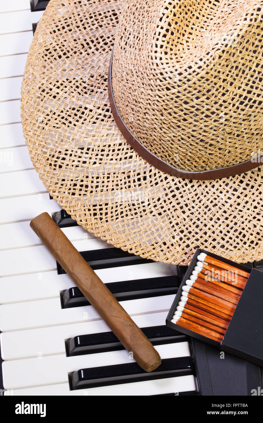 Dettaglio della tastiera di pianoforte,cappello di paglia e sigari di lusso Foto Stock