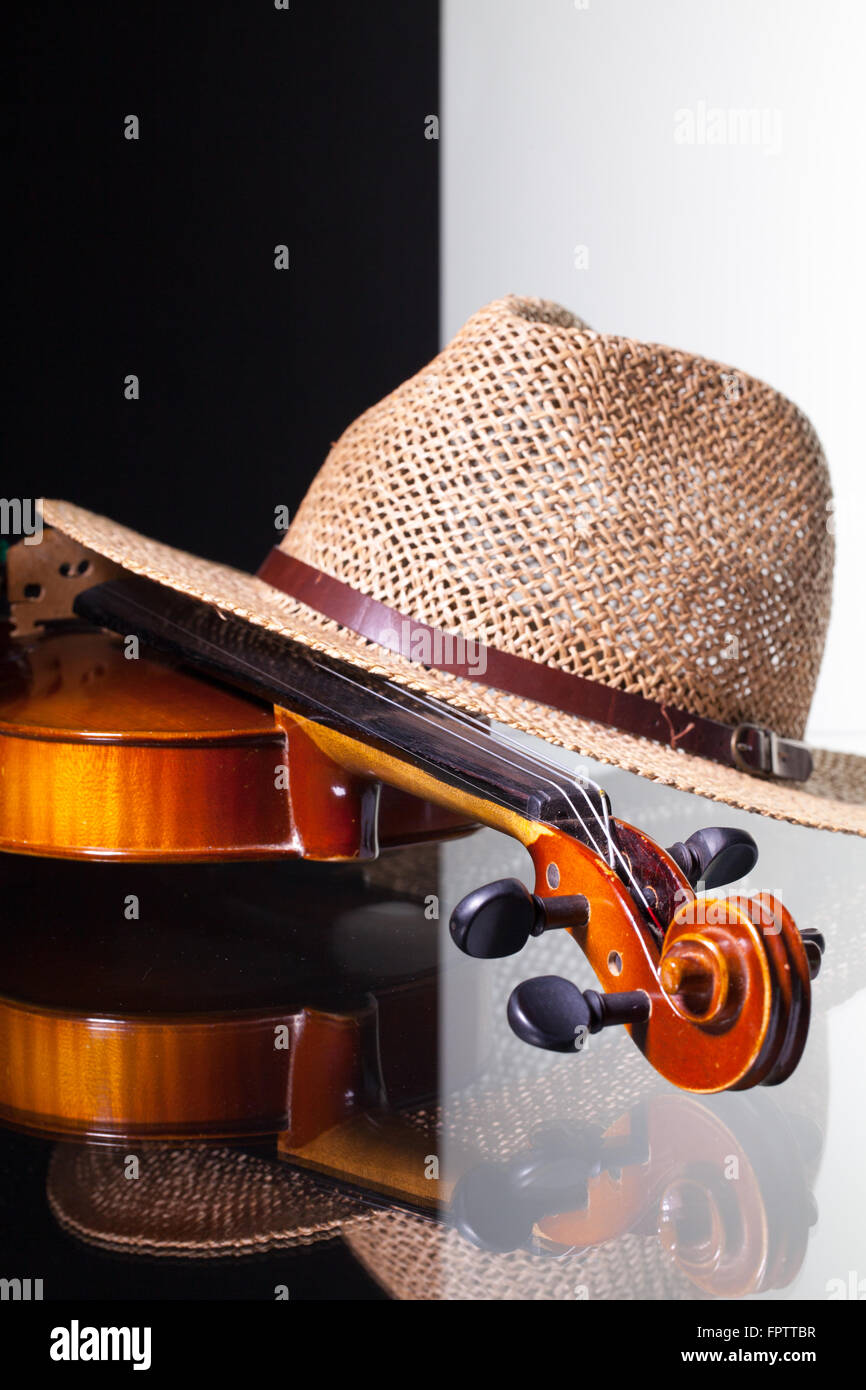 Vecchio violino e cappello di paglia isolato in bianco e nero e sfondo scrivania in vetro Foto Stock