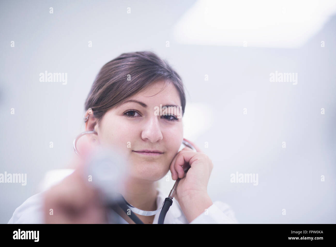 Ritratto di un giovane medico donna in ascolto del battito cardiaco da uno stetoscopio Freiburg im Breisgau, Baden-Württemberg, Germania Foto Stock