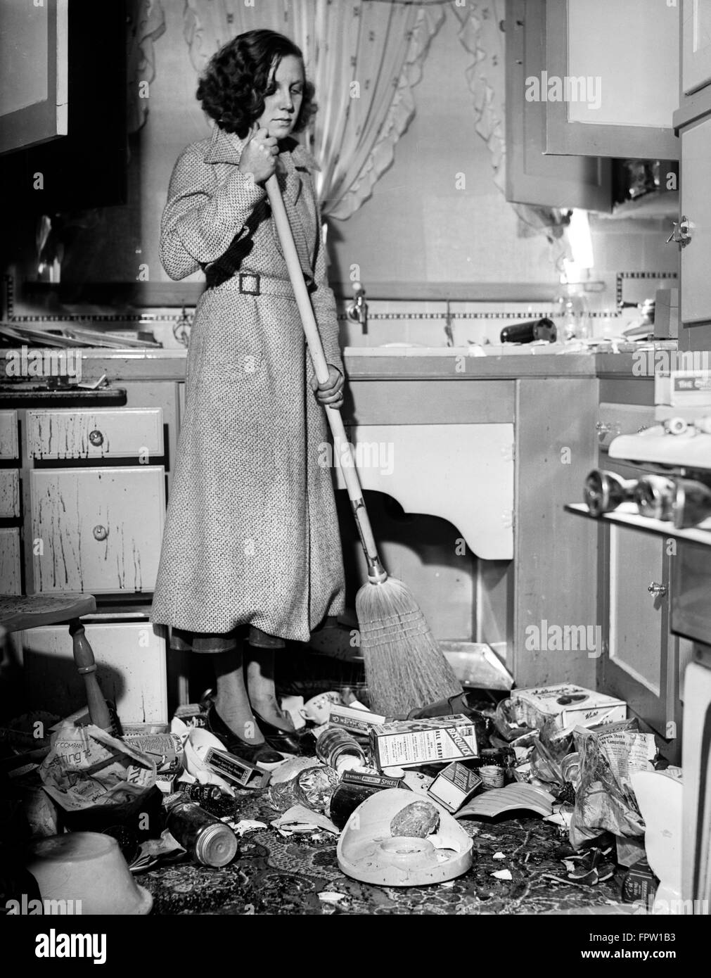 1930s DISTRESSED donna spazzando su cibo e cestino IN CUCINA POSTUMI DI MARZO 10 1933 TERREMOTO LONG BEACH CA USA Foto Stock