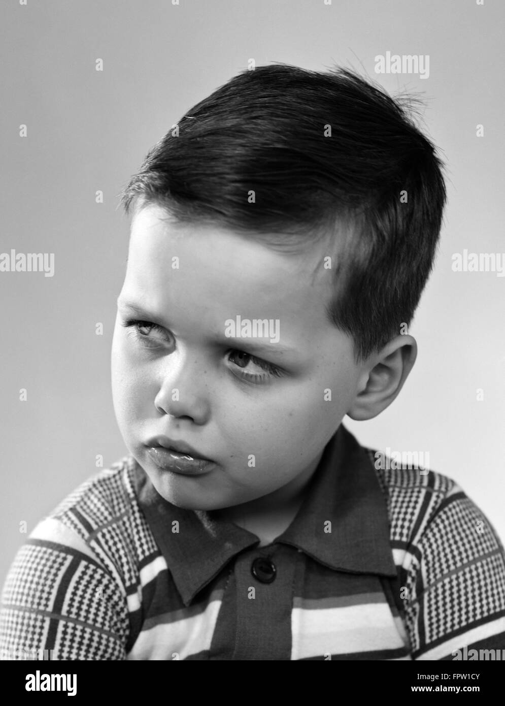 Anni Cinquanta ritratto accigliata ragazzo indossa STRIPED camicia a scacchi Foto Stock