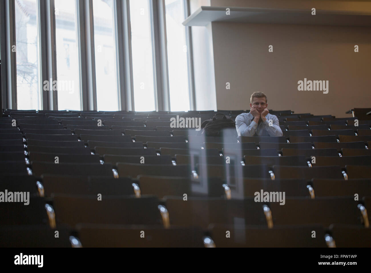 Annoiato studente di college seduto da solo nella sala conferenze e lezioni di ascolto di Freiburg im Breisgau, Baden-Württemberg, Germania Foto Stock