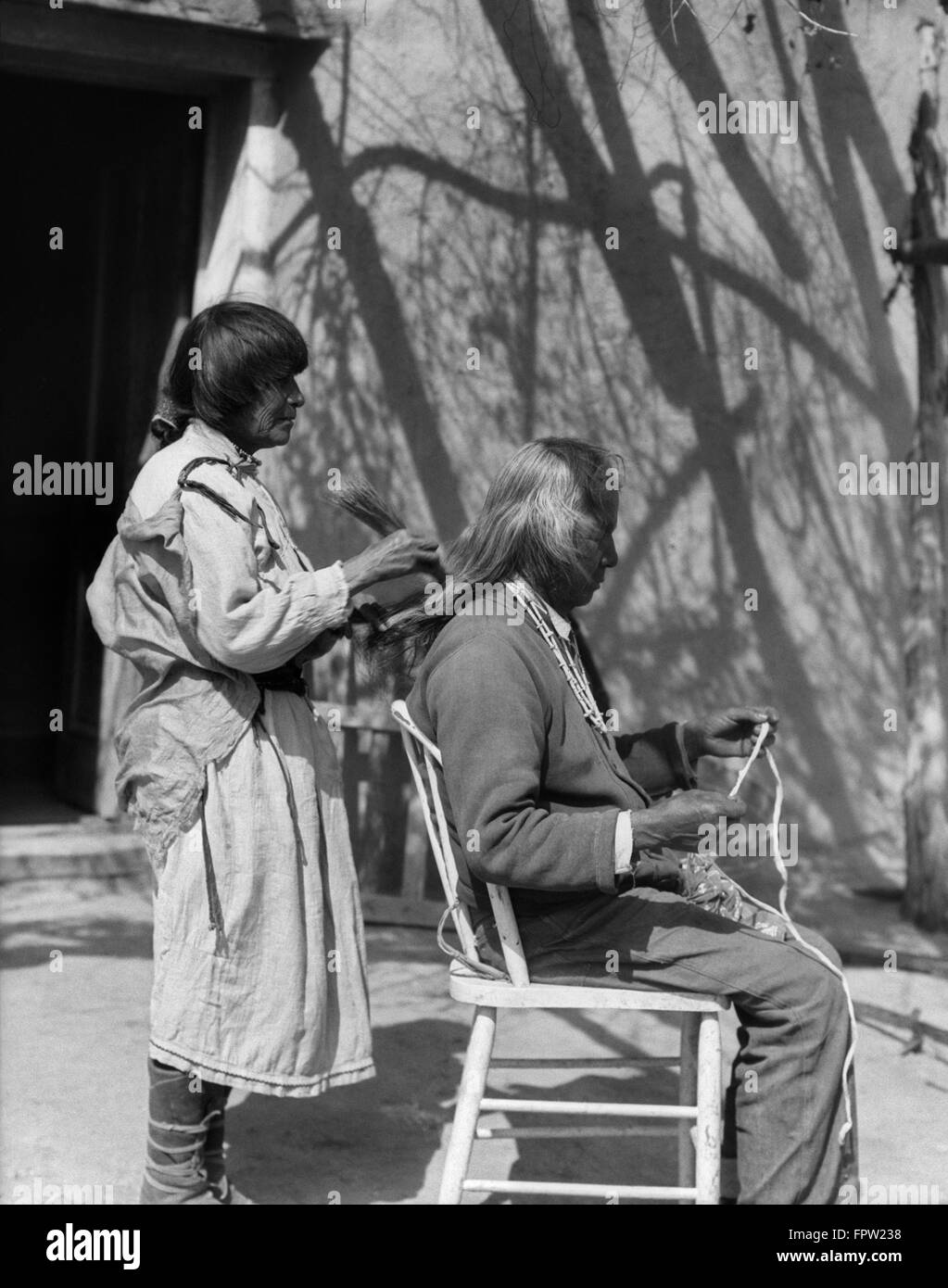 1930s Native American donna pettinatura dei capelli uomo anziano con pettine di paglia COCHITI PUEBLO NEL NUOVO MESSICO USA Foto Stock