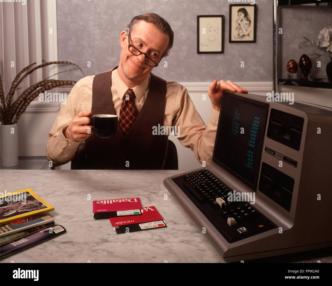 Anni ottanta orgoglioso uomo sorridente di bere il caffè in appoggio la sua mano sulla sua nuova Radio Shack TRS-80 III PERSONAL COMPUTER Foto Stock