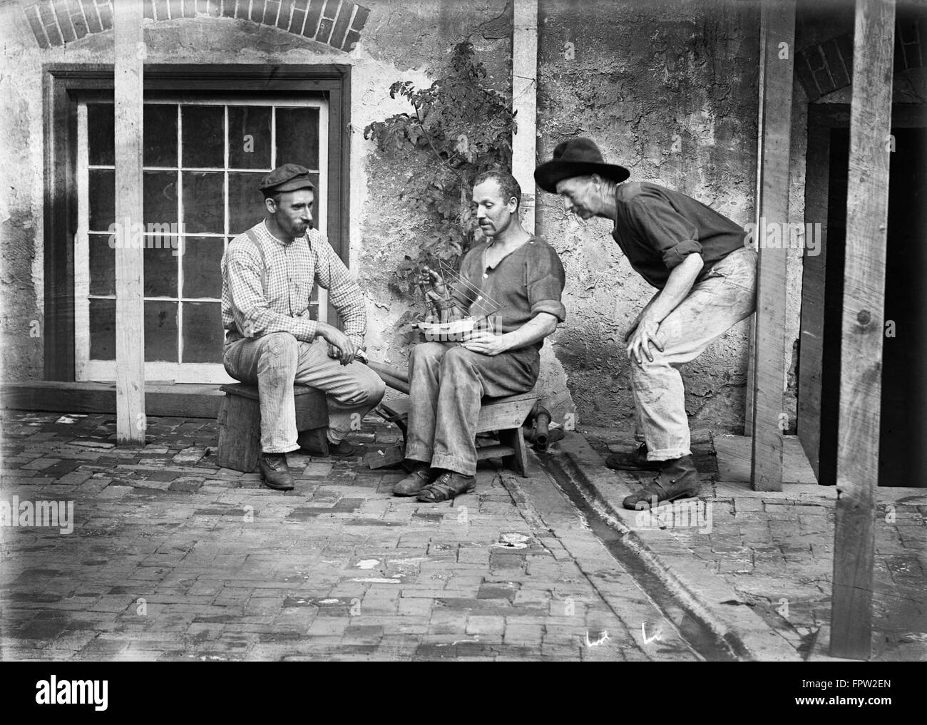 1900s tre uomini seduti a casa di un uomo con modello di nave IN GIRO Foto Stock