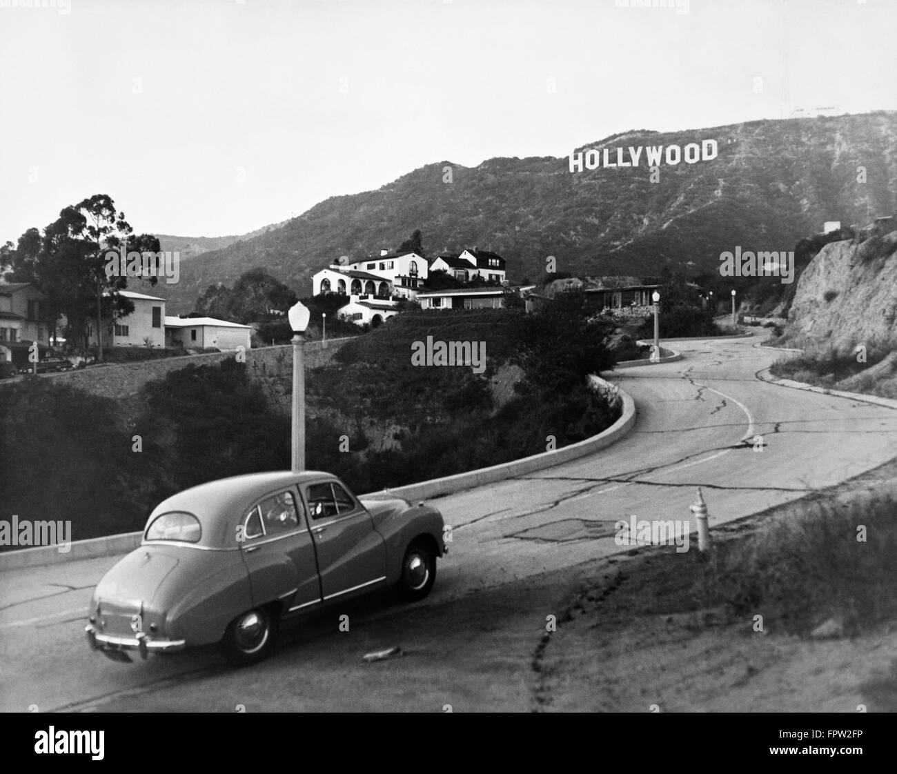 1950 Austin auto guidando su colline di Hollywood con Hollywood Sign in distanza Foto Stock