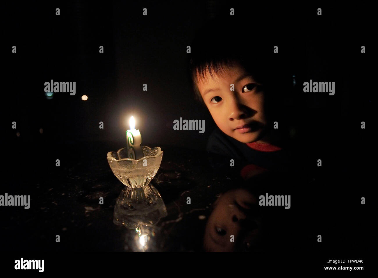 6 anno vecchio Brendan partecipa al decimo Earth Hour con un lume di candela su Marzo 19, 2016. Foto Stock