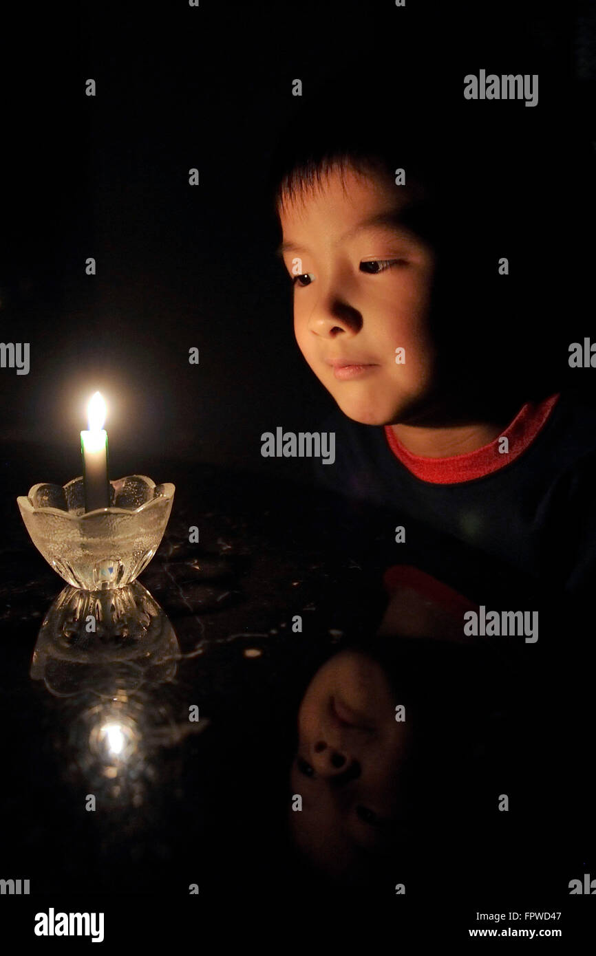 6 anno vecchio Brendan partecipa al decimo Earth Hour con un lume di candela su Marzo 19, 2016. Foto Stock