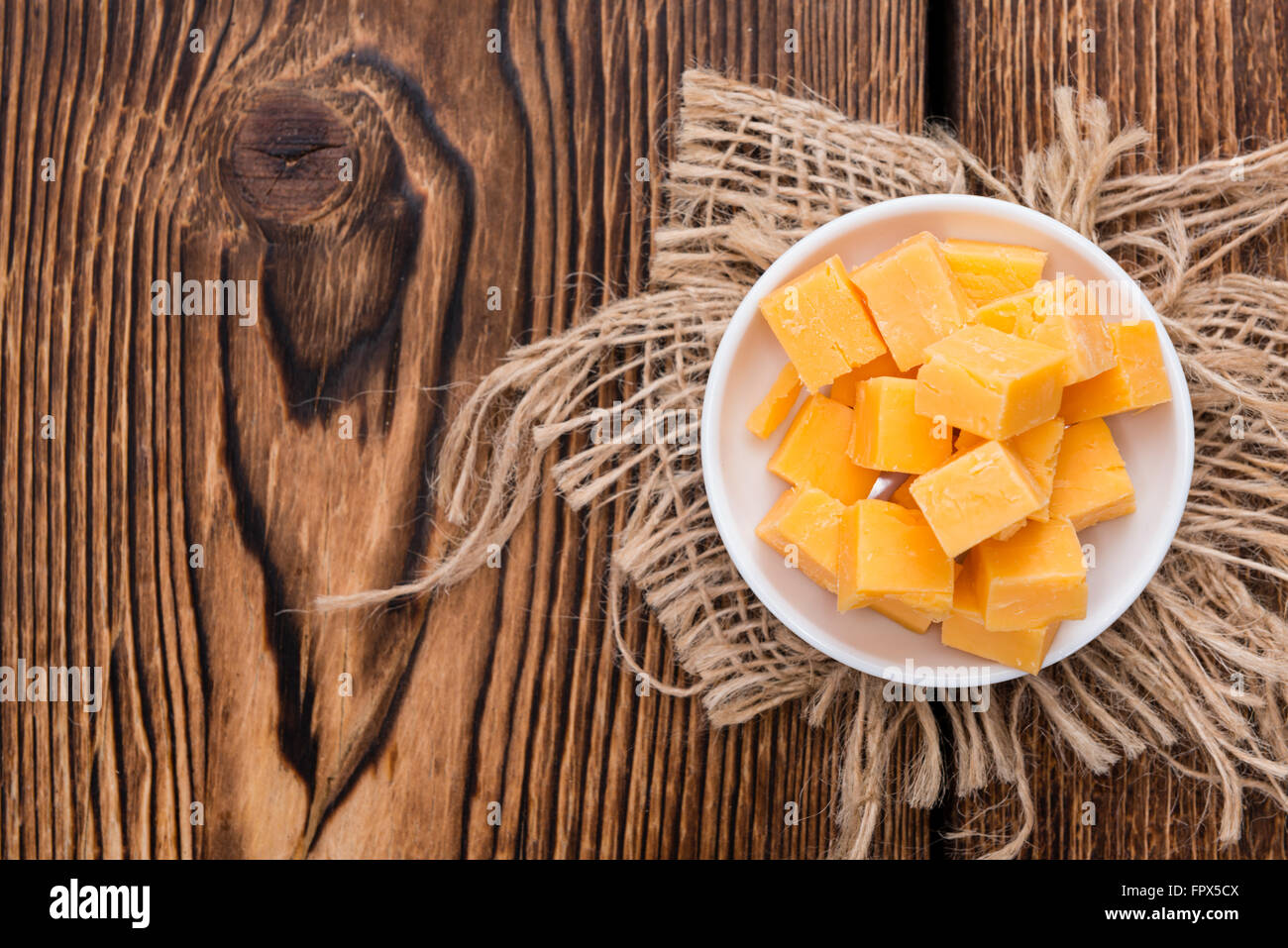 Pezzi di formaggio Cheddar (close-up shot) su un vecchio tavolo in legno Foto Stock