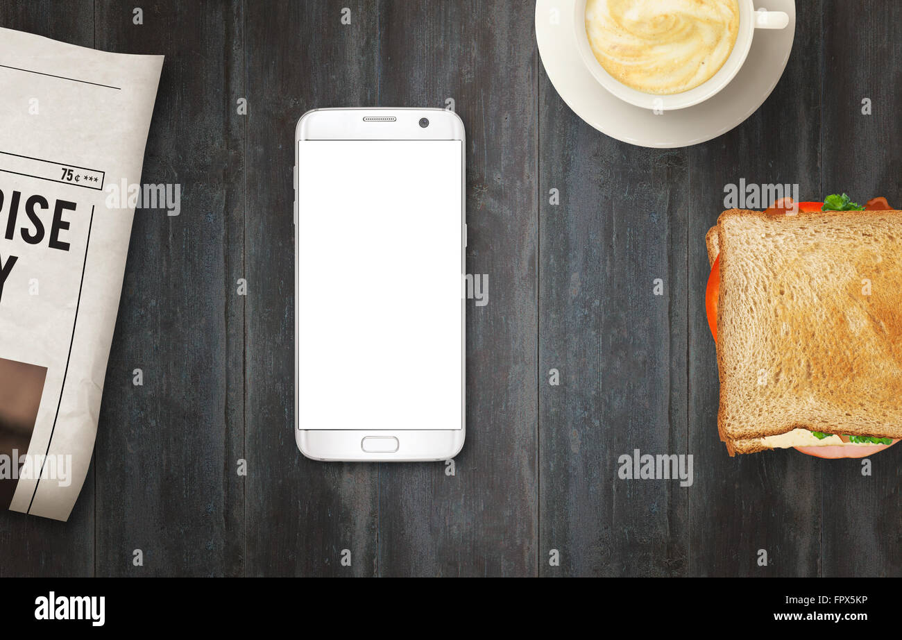 Smart Phone con display isolato per mockup sul tavolo. Quotidiani, caffè e sandwich sul tavolo. Vista dall'alto. Foto Stock