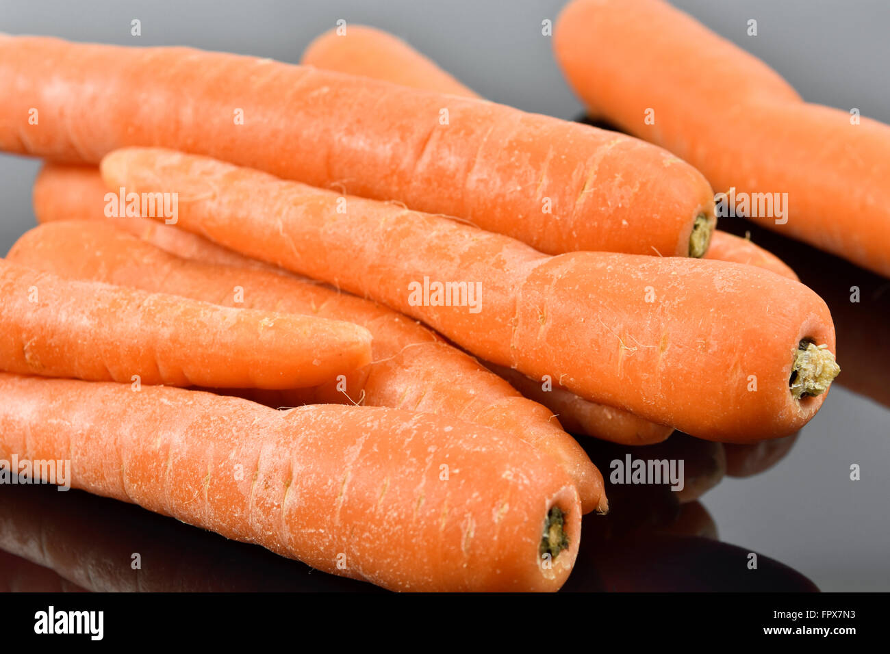Pila di carote sul buio superficie riflettente Foto Stock