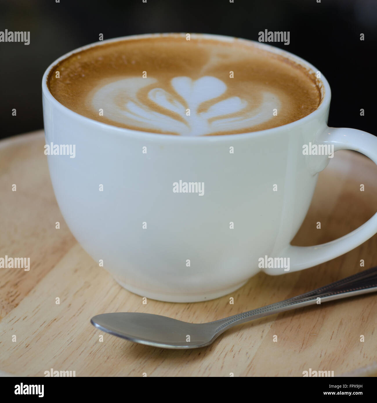 Una tazza di latte art sul piatto di legno Foto Stock