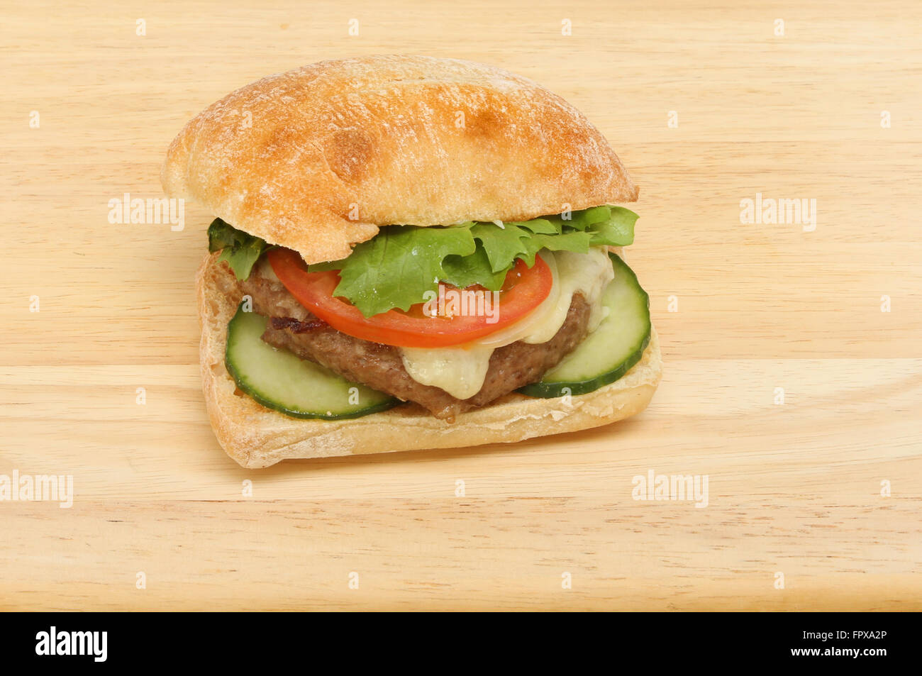 Cheeseburger con insalata in una ciabatta rotolo su una tavola di legno Foto Stock